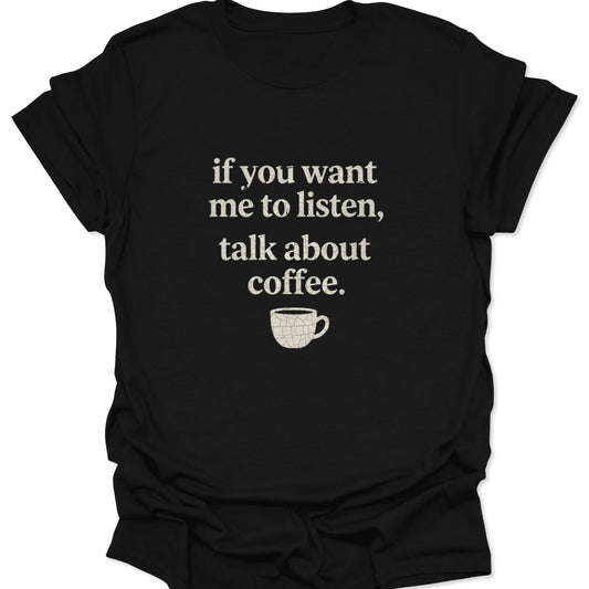A black graphic t-shirt featuring the text "if you want me to listen, talk about coffee" in a distressed white serif font above a small, cracked white coffee cup illustration.
