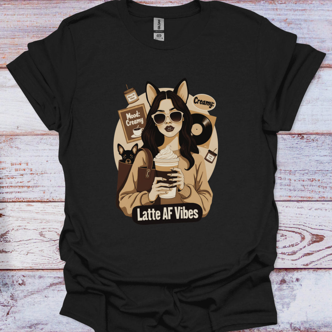 Black t-shirt with a graphic of a woman holding a coffee cup and text 'Latte AF Vibes' on a wooden surface.