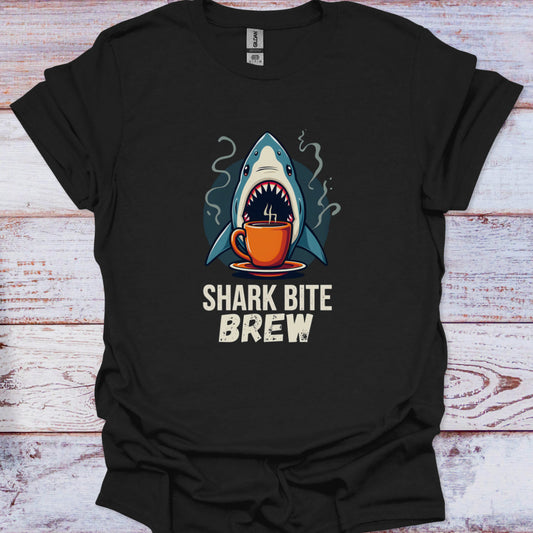 Black t-shirt with a shark holding a coffee cup graphic and 'Shark Bite Brew' text on a wooden surface.