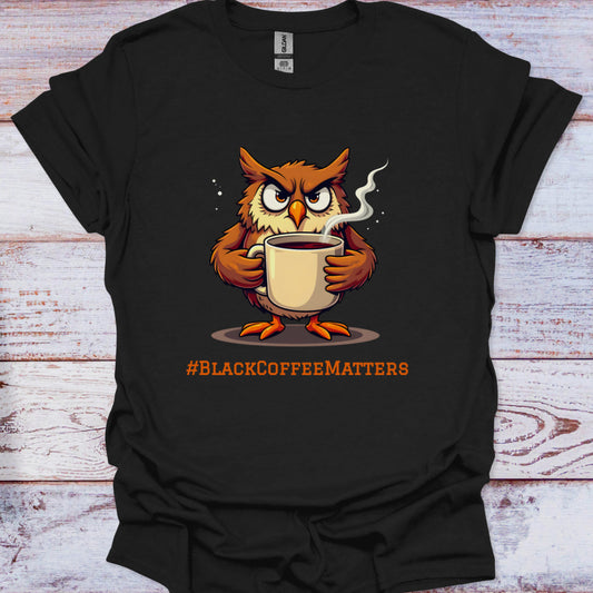 Black t-shirt with an owl holding a coffee cup and '#BLACKCOFFEEMATTERS' text on a wooden surface