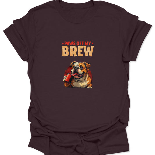 Dark chocolate brown t-shirt with a detailed graphic of an angry bulldog gripping a red coffee cup, text reads "PAWS OFF MY BREW." Cross-niche coffee and pet lover design.