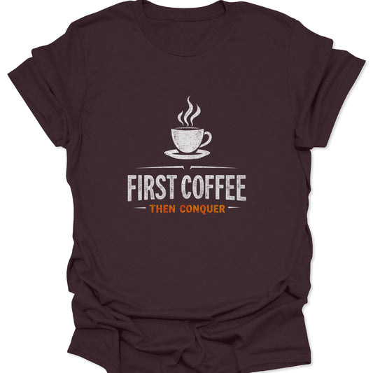 Motivational graphic t-shirt with a steaming coffee cup design and "First Coffee Then Conquer" text printed in white and orange on a rich, dark chocolate brown material.
