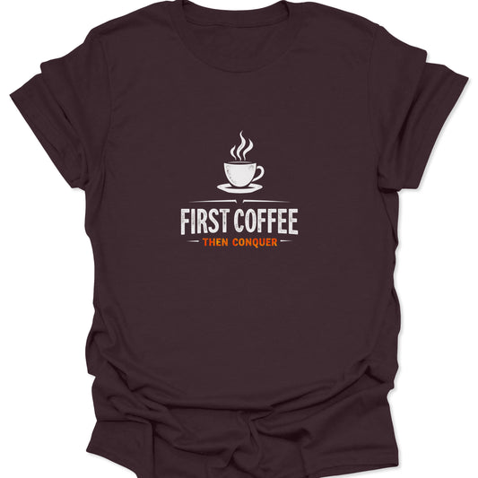 Motivational graphic t-shirt with a steaming coffee cup design and "First Coffee Then Conquer" text printed in white and orange on a rich, dark chocolate brown material.