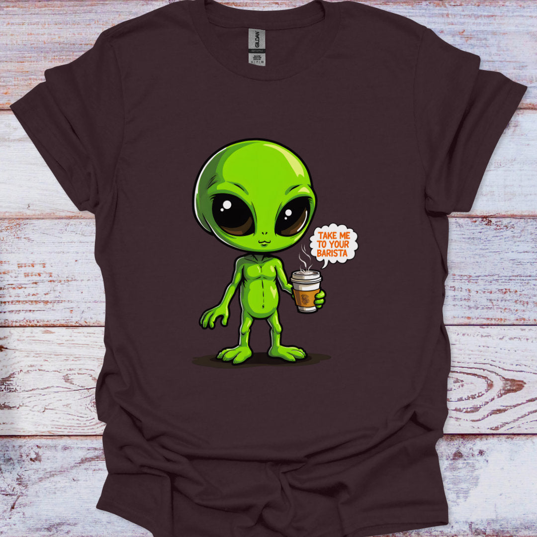 Brown t-shirt with a green alien holding a coffee cup graphic on a wooden surface