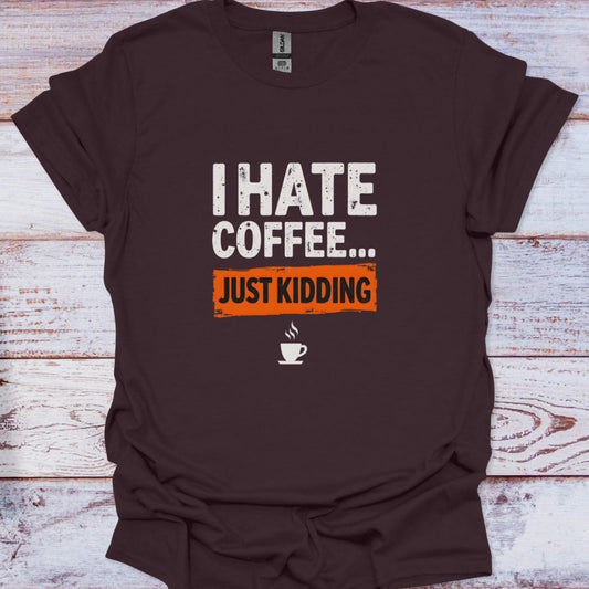 Brown t-shirt with 'I Hate Coffee... Just Kidding' text on a wooden surface