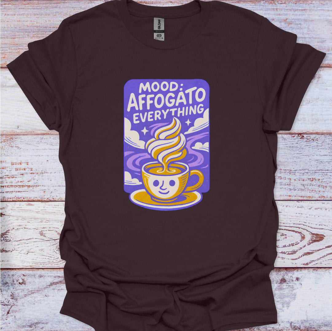 Brown t-shirt with a graphic design of a coffee cup and text on a wooden surface