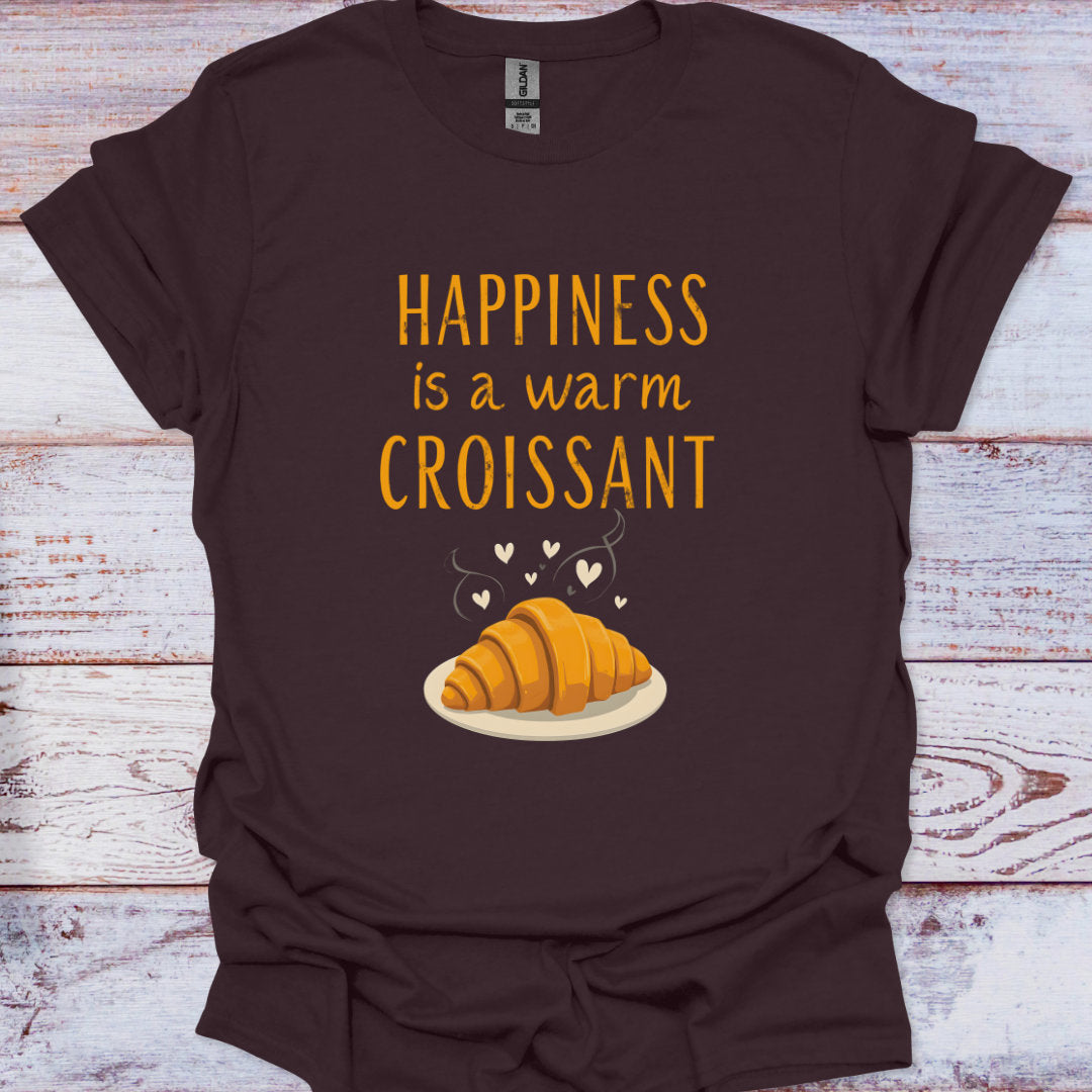 Brown t-shirt with a croissant graphic and text on a wooden surface