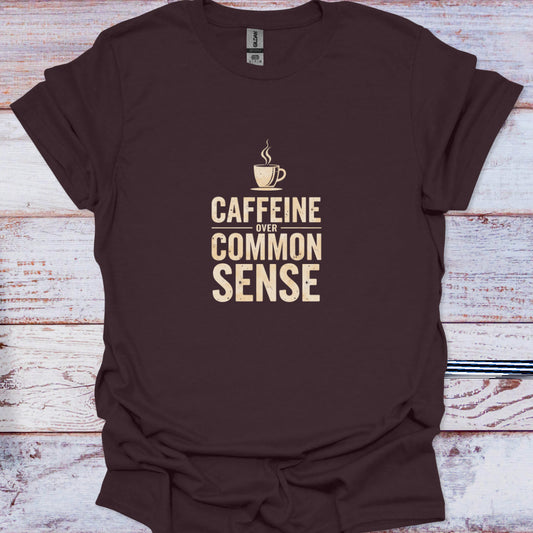 Dark brown tee showing vintage cream typography "Caffeine Over Common Sense" and steaming mug graphic.
