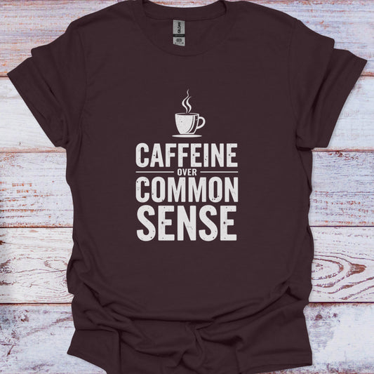 Brown t-shirt with 'CAFFEINE OVER COMMON SENSE' text and coffee cup graphic on a wooden surface