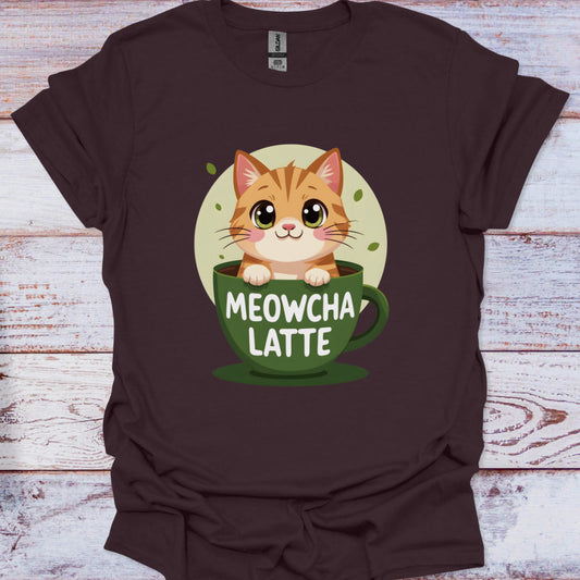 Brown t-shirt with a cat in a coffee cup graphic and 'MEOWCHA LATTE' text on a wooden surface.