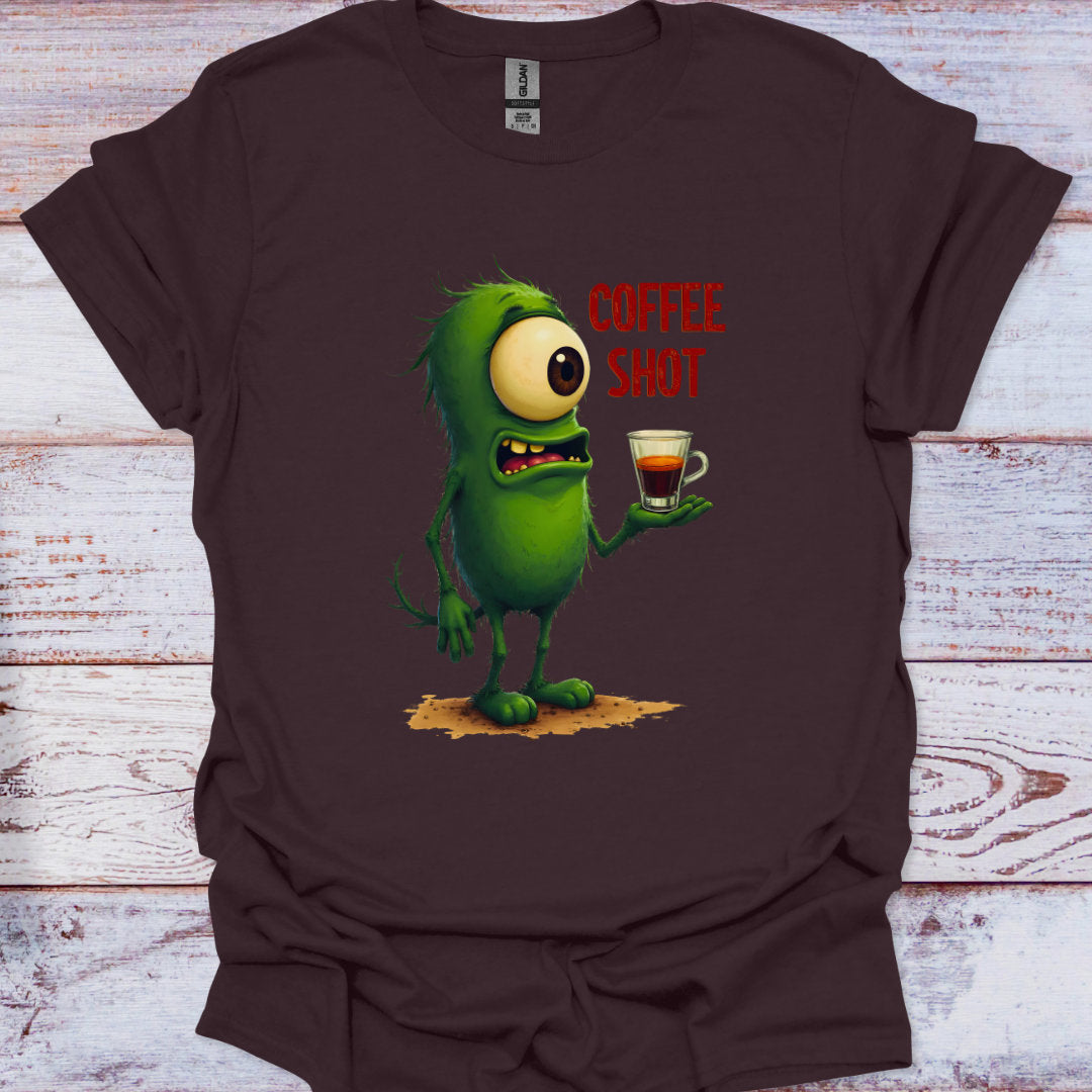Brown t-shirt with a green monster holding a coffee shot graphic on a wooden surface
