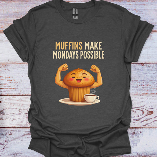 Dark gray t-shirt with a cartoon muffin flexing muscles and text 'Muffins Make Mondays Possible' on a wooden surface.