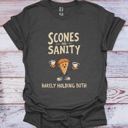 Dark gray t-shirt with scone graphic and text 'Scones and Sanity Barely Holding Both' on a wooden surface.