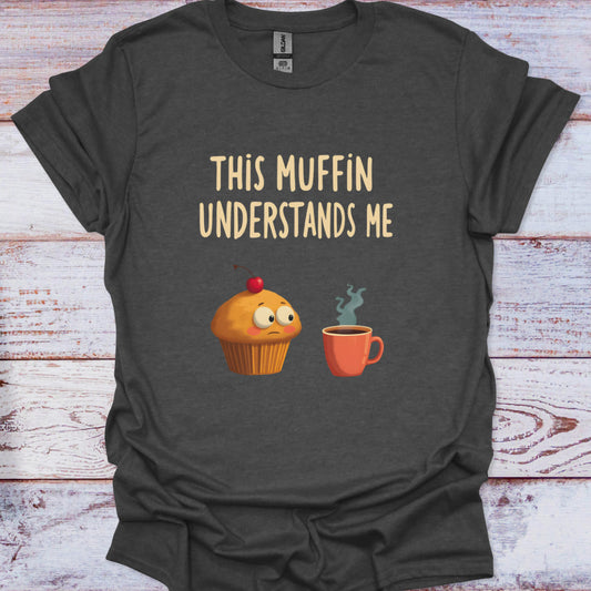 Dark gray t-shirt with a cartoon cupcake and coffee cup graphic and text 'This Muffin Understands Me' on a wooden surface.