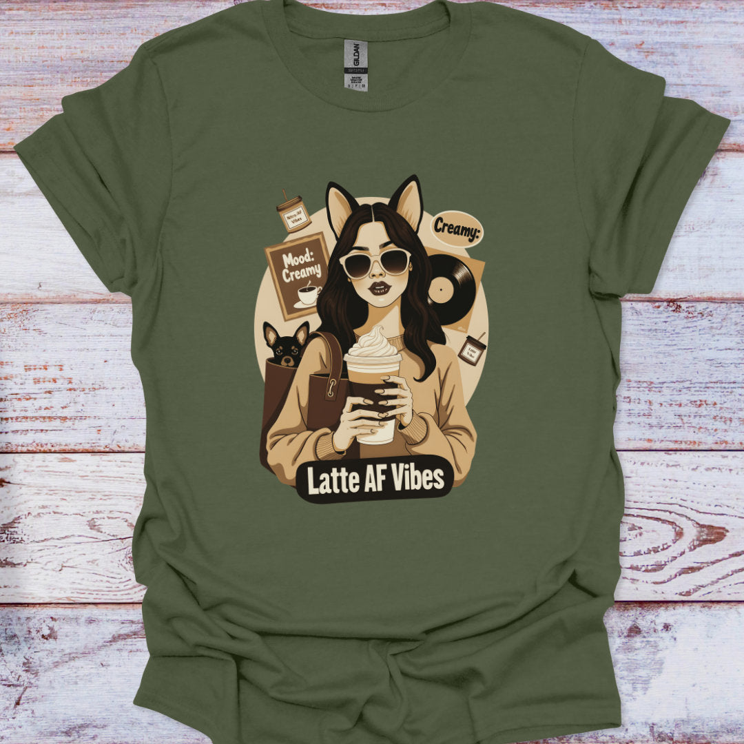 Green t-shirt with a graphic of a person holding a coffee cup and text 'Latte AF Vibes' on a wooden surface.