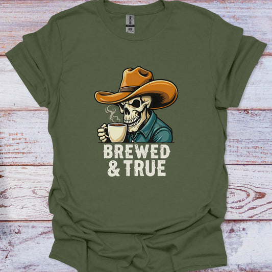 Green t-shirt with a skull wearing a cowboy hat and holding a coffee cup, text 'BREWED & TRUE' on a wooden surface.