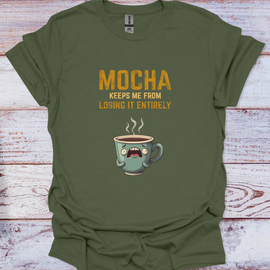 Green t-shirt with a coffee cup graphic and text on a wooden surface