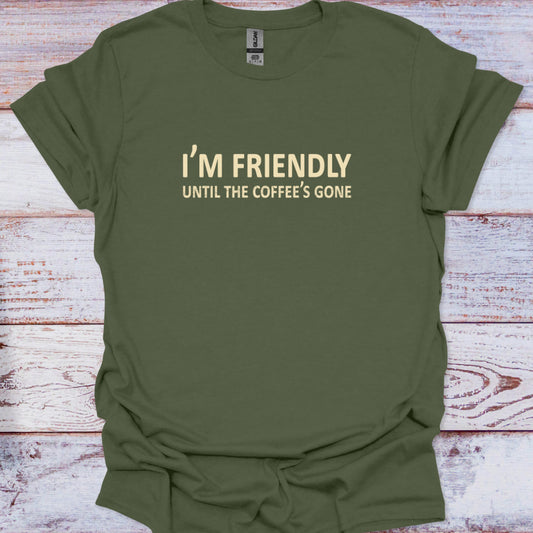 Green t-shirt with text 'I'm friendly until the coffee's gone' on a wooden surface