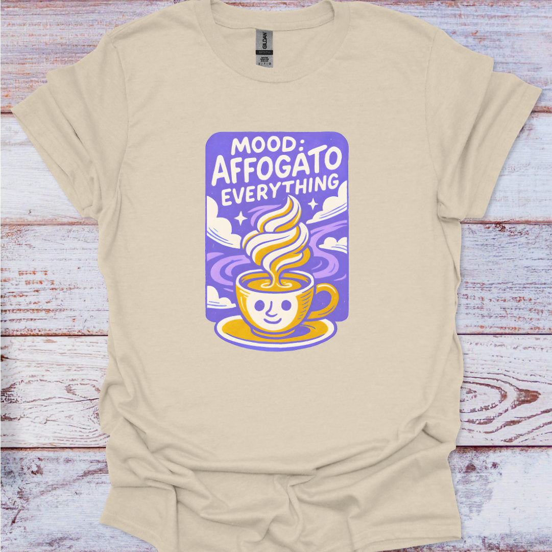 Beige t-shirt with a graphic design of a coffee cup and text on a wooden surface
