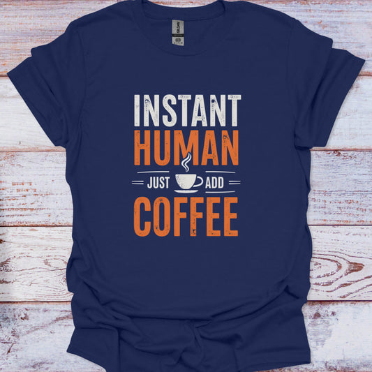 Navy blue t-shirt with 'Instant Human Just Add Coffee' text on a wooden surface