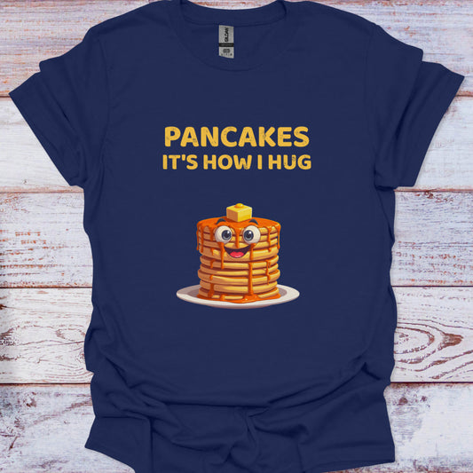 Navy blue t-shirt with cartoon pancakes and text 'Pancakes It's How I Hug' on a wooden surface