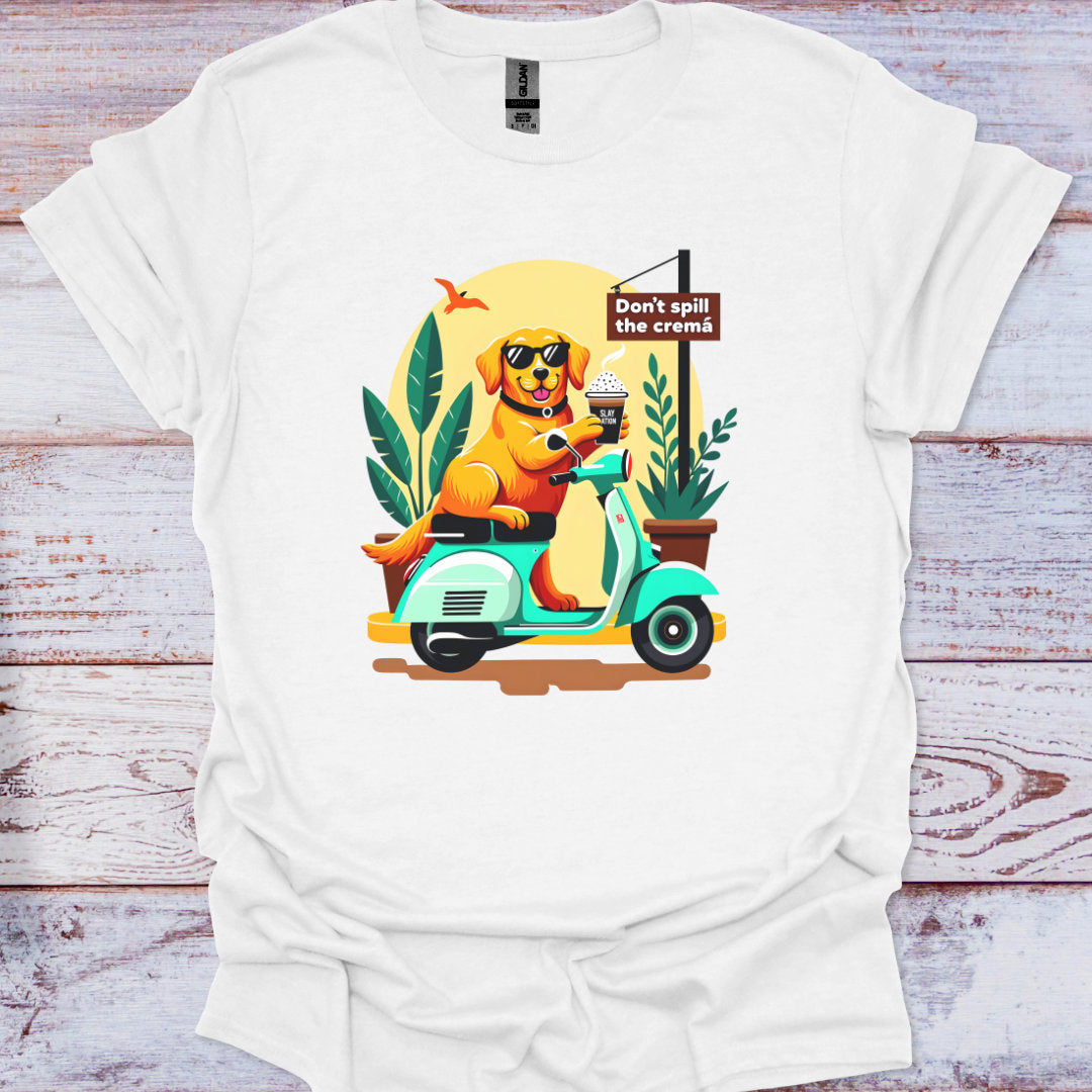 White t-shirt with a colorful graphic of a dog on a scooter and a potted plant, on a wooden surface.