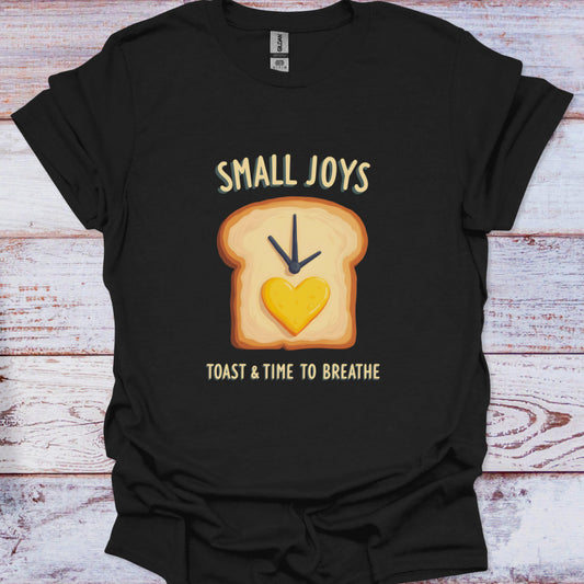 Black t-shirt with a graphic of toast and a heart, text 'Small Joys Toast & Time to Breathe' on a wooden surface.
