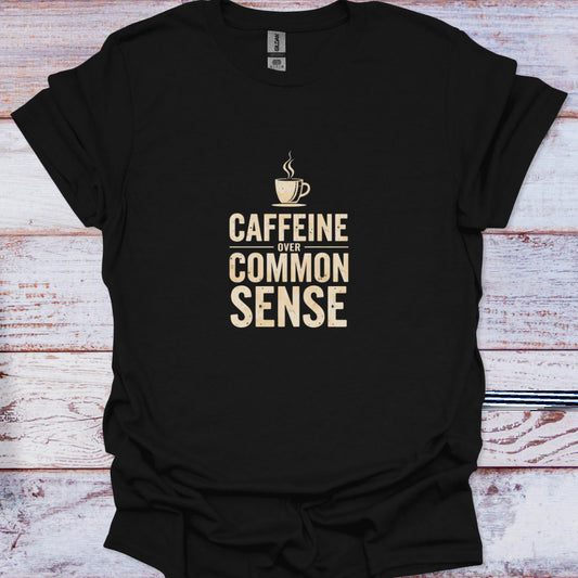 Flat lay of black t-shirt featuring beige distressed text reading "Caffeine Over Common Sense" with a coffee cup icon.