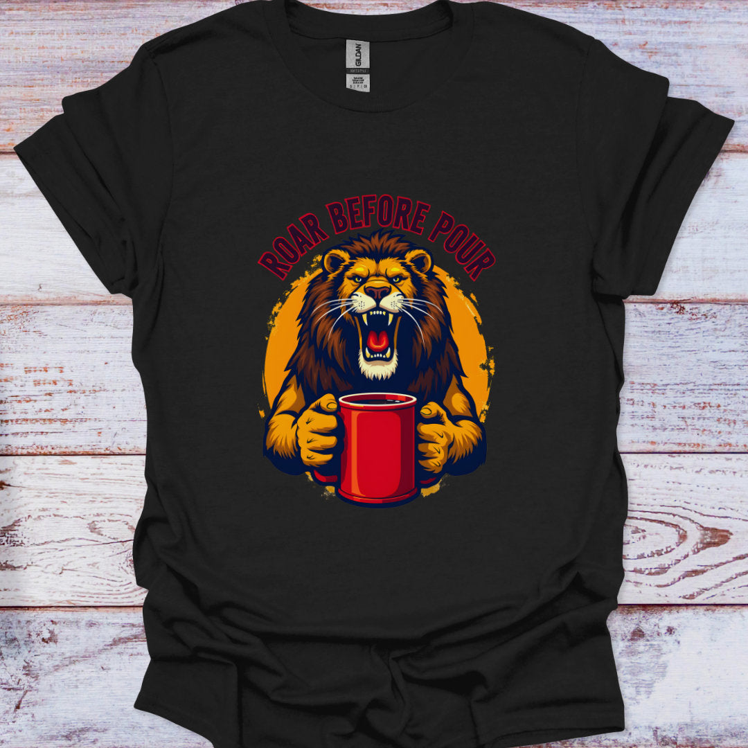 Black t-shirt with a graphic of a lion holding a red cup and 'Roar Before Pour' text on a wooden surface.