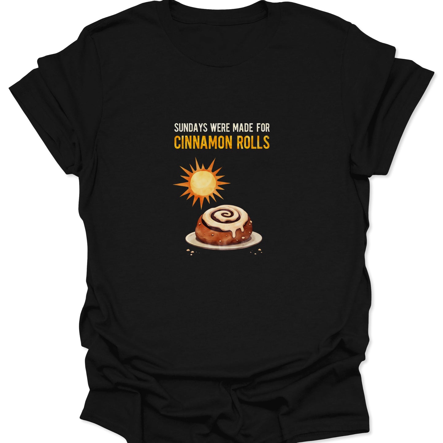 Graphic t-shirt in black featuring a cinnamon roll basking in sunlight with text "Sundays Were Made For Cinnamon Rolls".