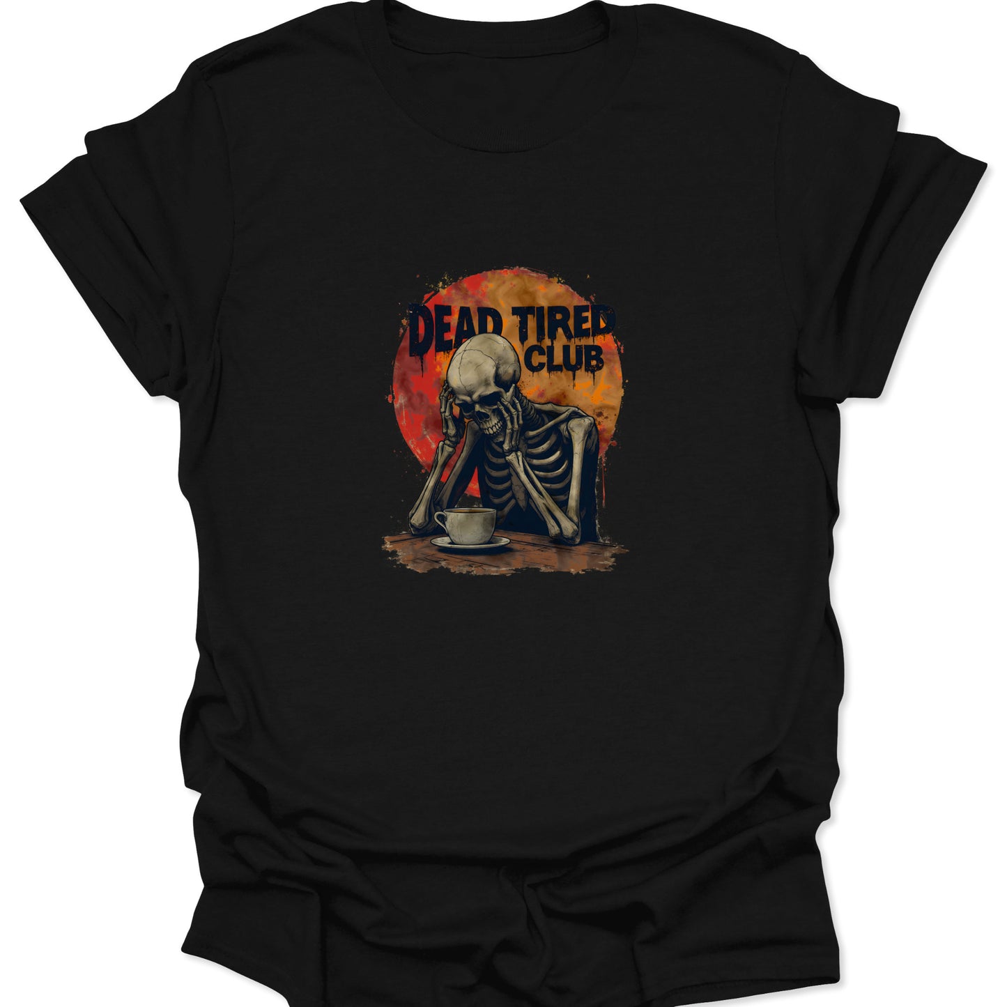 Close-up of black t-shirt with a highly detailed, dark-humor graphic: a skeleton slumping over a coffee cup, centered in a distressed red and orange apocalyptic circle, with the text "DEAD TIRED CLUB."
