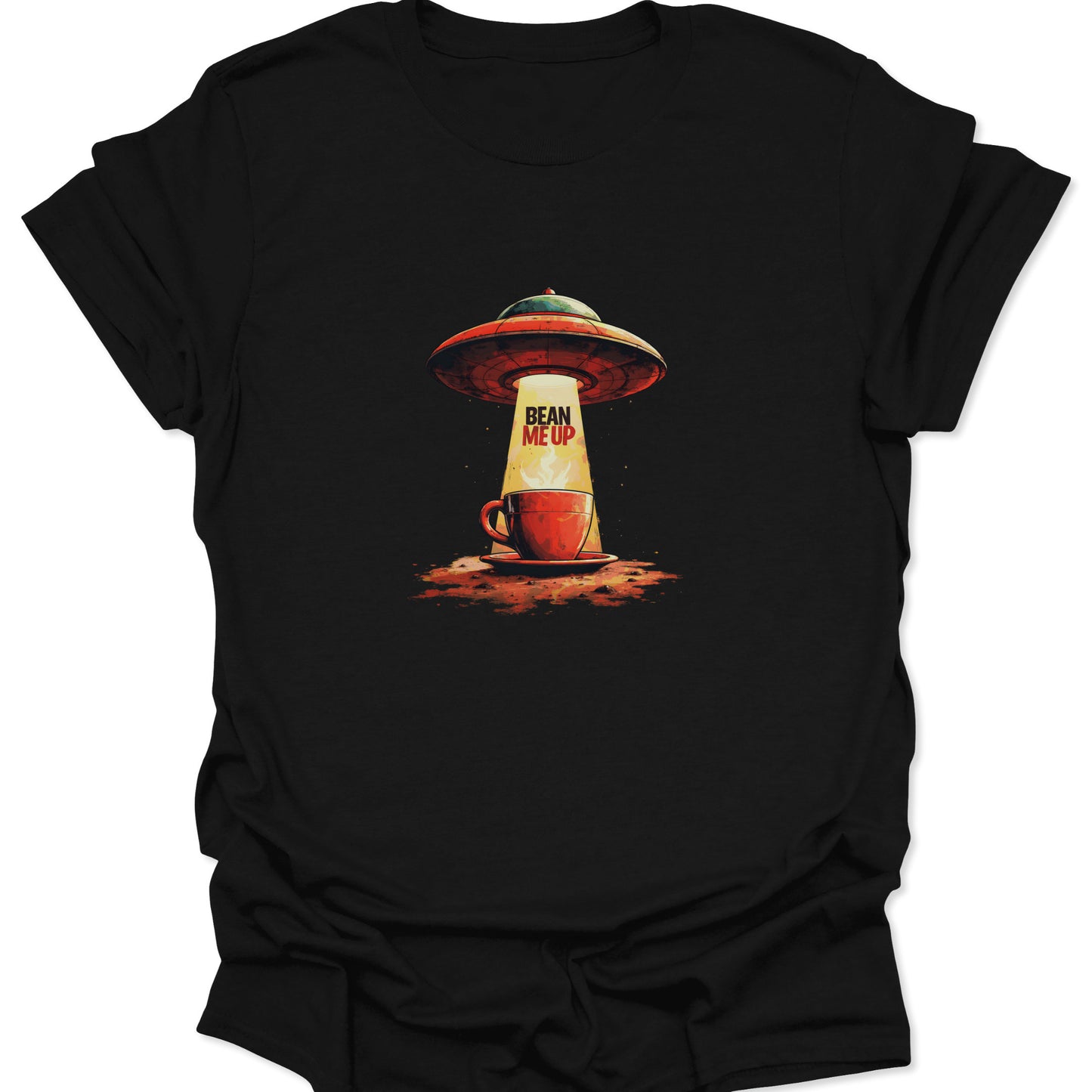 Close-up of black cotton t-shirt featuring the "Bean Me Up" coffee abduction graphic: a red and green flying saucer tractor-beaming a red coffee cup with bright yellow light.