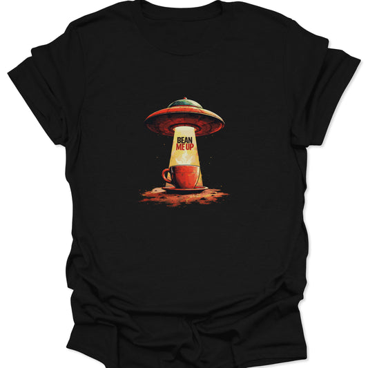 Close-up of black cotton t-shirt featuring the "Bean Me Up" coffee abduction graphic: a red and green flying saucer tractor-beaming a red coffee cup with bright yellow light.
