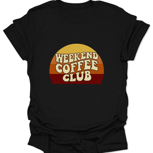 Graphic tee on a black fabric background featuring a retro sunset semi-circle with "Weekend Coffee Club" text in a cream-colored, bubbly 70s font.