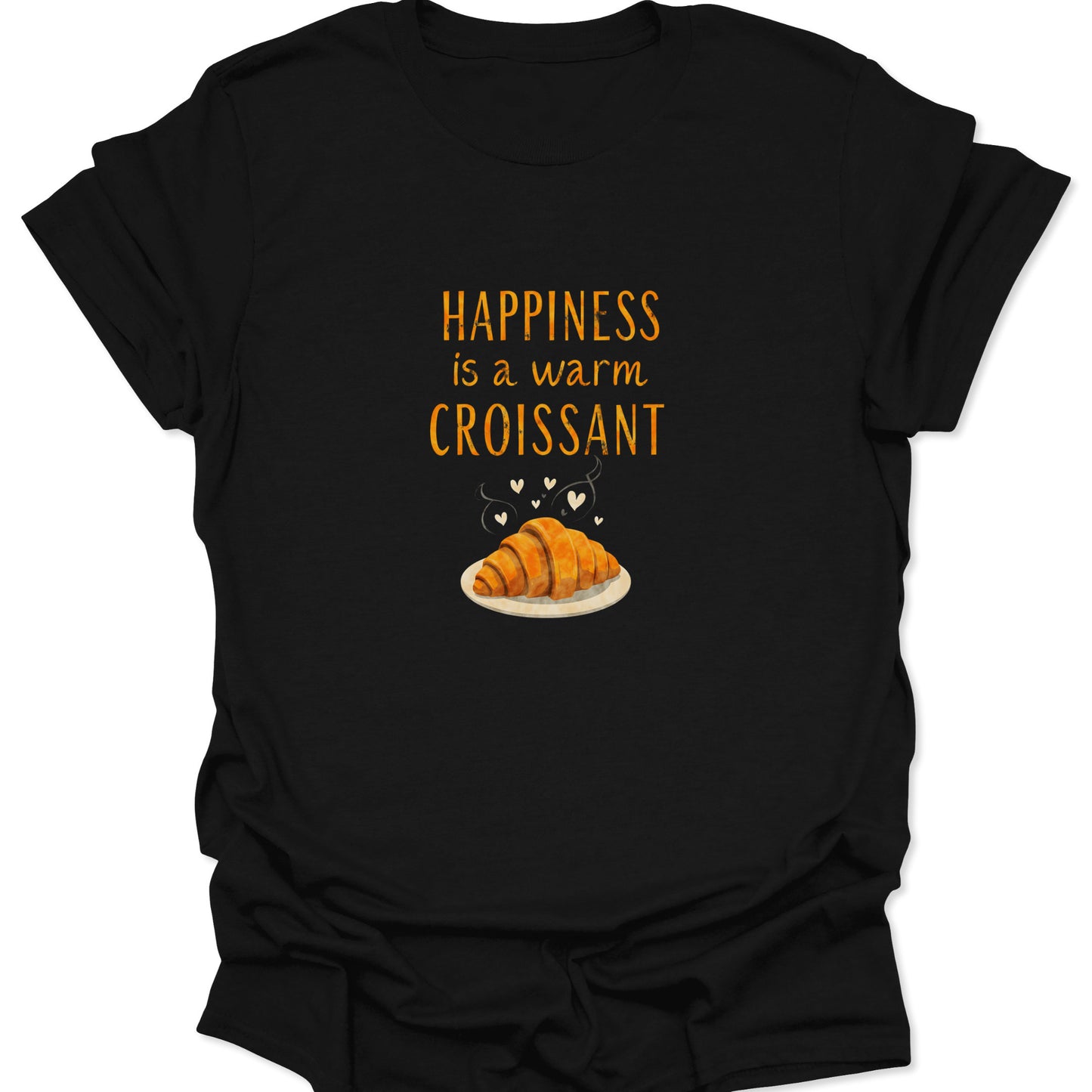 Black t-shirt with a centered, warm orange text reading "Happiness is a warm Croissant" above a detailed illustration of a steaming golden-brown French pastry on a plate with tiny white hearts.