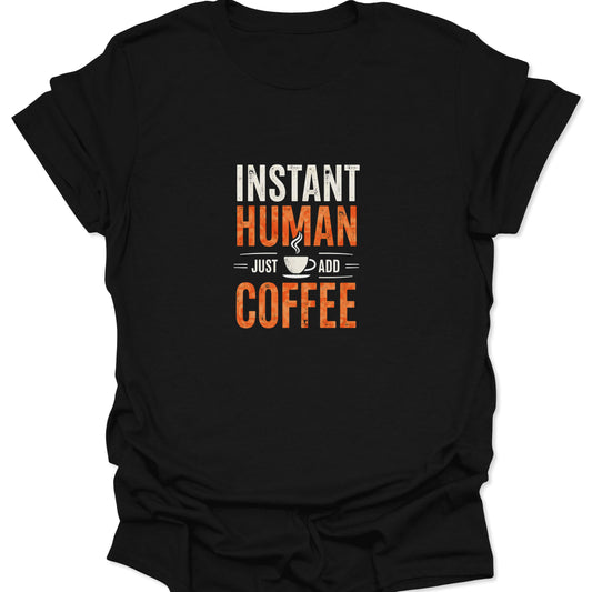 Black crewneck tee with a crisp white and burnt orange distressed graphic saying "INSTANT HUMAN = JUST ADD = COFFEE" centered with a coffee mug icon.
