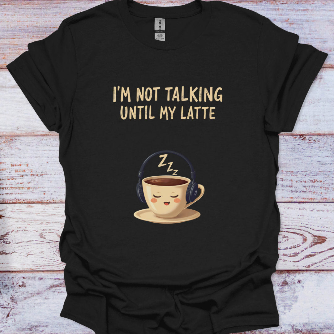 Black t-shirt with a cartoon coffee cup and text 'I'm not talking until my latte' on a wooden surface.