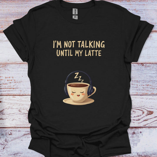 Black t-shirt with a cartoon coffee cup and text 'I'm not talking until my latte' on a wooden surface.