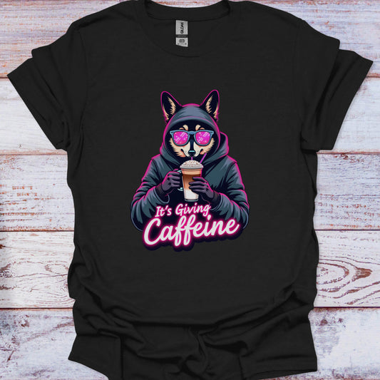 Black t-shirt with a graphic of a fox in a hoodie holding a coffee cup and text 'It's Giving Caffeine' on a wooden surface.