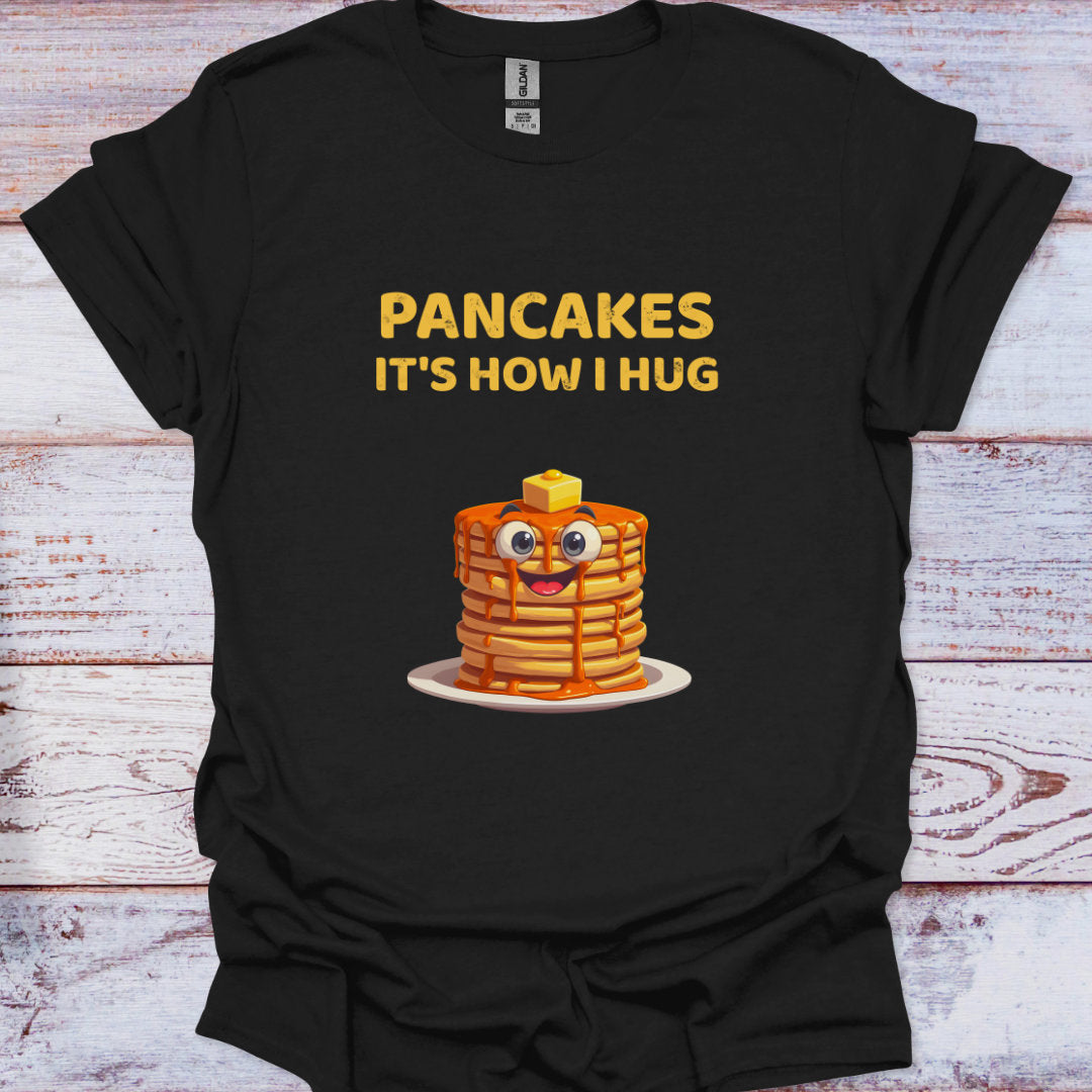 Black t-shirt with cartoon pancakes and text 'Pancakes it's how I hug' on a wooden surface