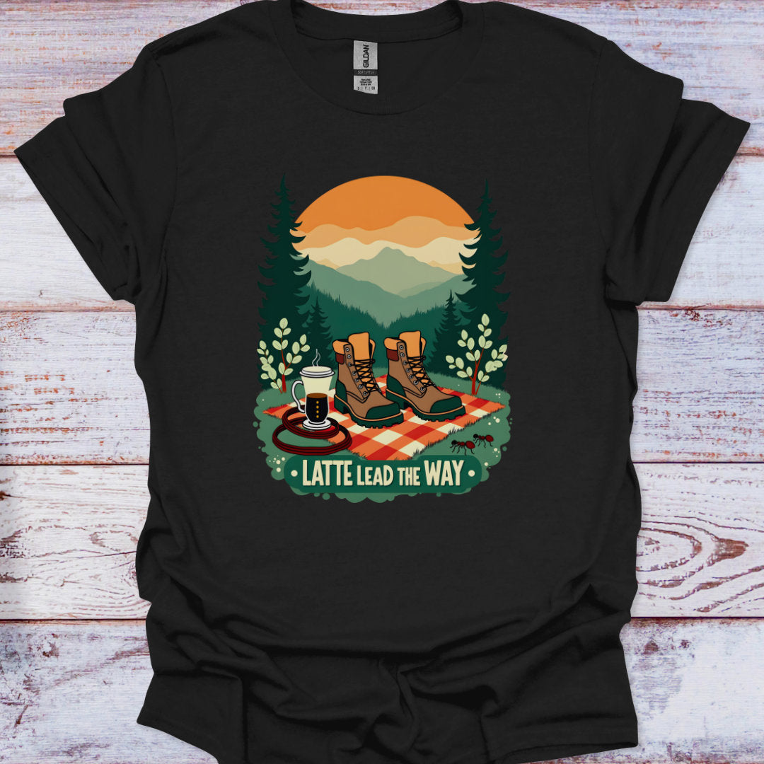 Black t-shirt with a graphic design of hiking boots, a coffee cup, and 'Latte Lead the Way' text on a wooden surface.