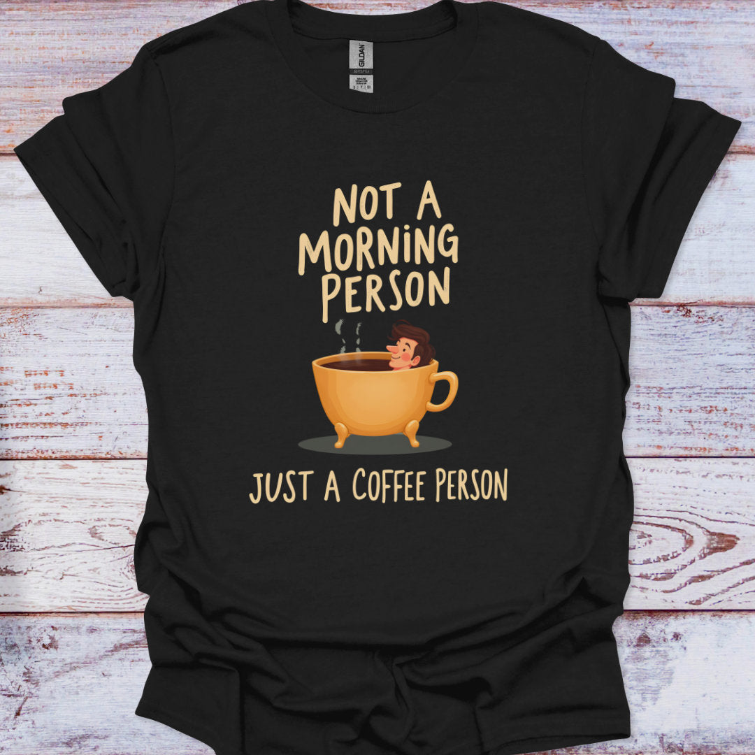 Black t-shirt with a graphic of a coffee cup and text 'Not a morning person, just a coffee person' on a wooden surface.