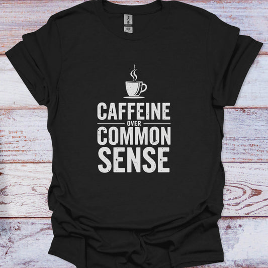 Black t-shirt with 'CAFFEINE OVER COMMON SENSE' text and coffee cup graphic on a wooden surface