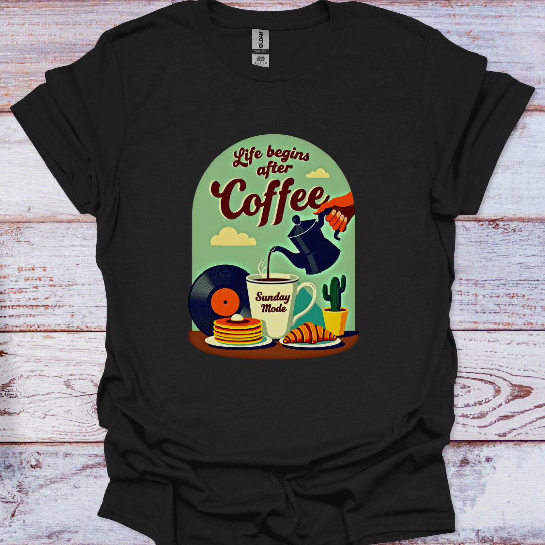 Black t-shirt with a colorful graphic design featuring coffee-themed illustrations on a wooden surface.