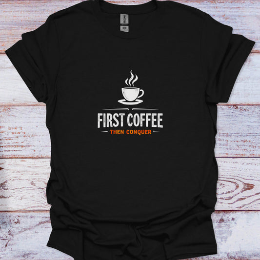 High-contrast white and orange graphic tee featuring a coffee cup and the motivational phrase "First Coffee Then Conquer" on a solid black fabric.