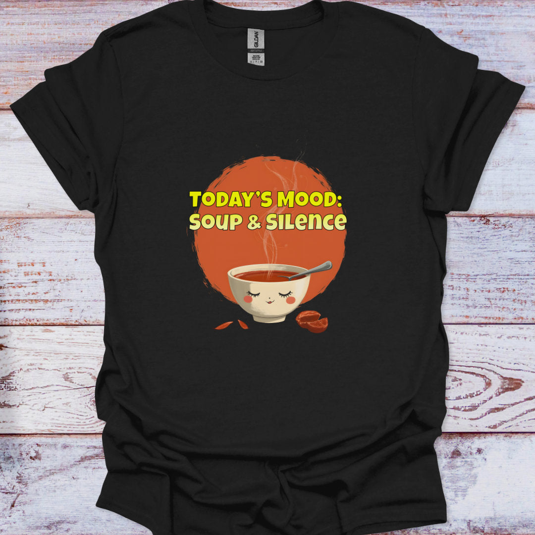 Black t-shirt with a graphic of a bowl of soup and text 'TODAY'S MOOD: SOUP & SILENCE' on a wooden surface.