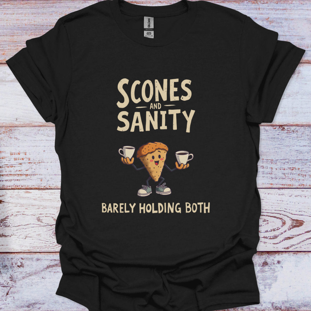 Black t-shirt with 'Scones and Sanity Barely Holding Both' graphic design on a wooden surface