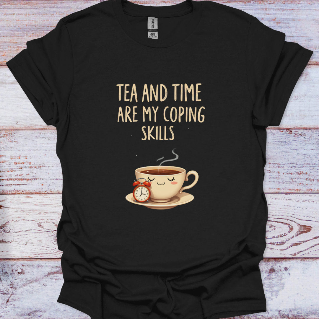Black t-shirt with a graphic of a tea cup and clock, and text 'Tea and time are my coping skills' on a wooden surface.