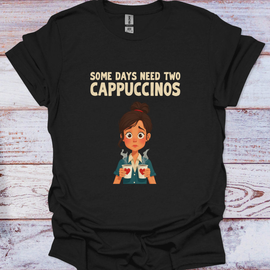 Black t-shirt with cartoon character and text 'Some days need two Cappuccinos' on a wooden surface