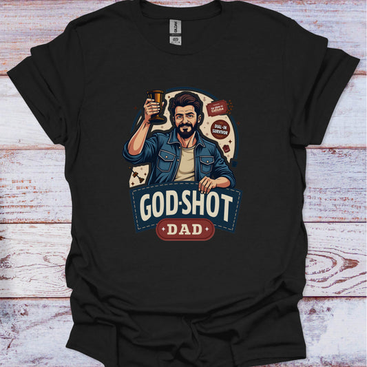 Black t-shirt with a graphic of a man holding a beer and text 'GOD-SHOT DAD' on a wooden surface.